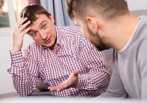 man discussing problems with friend while sitting on sofa at home | hoarding homeowner
