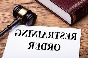 restraining order written on paper with gavel and law book background | hoa harassment law